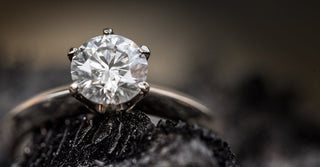 Close up of a brilliant round cut moissanite solitaire ring in a classic prong setting, showcasing exceptional sparkle, fire and diamond like brilliance.