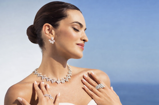 Elegant woman in profile wearing diamond necklace, earrings and rings in soft natural light