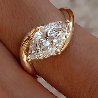 Marquise diamond set horizontally on a curved yellow gold band, designed with a sleek modern style.
