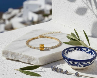 Yellow diamond tennis bracelet styled on a white stone surface with Mediterranean elements, inspired by Santorini wedding aesthetics.