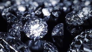 Close-up of multiple round brilliant cut diamonds sparkling under light, scattered across a dark reflective surface.